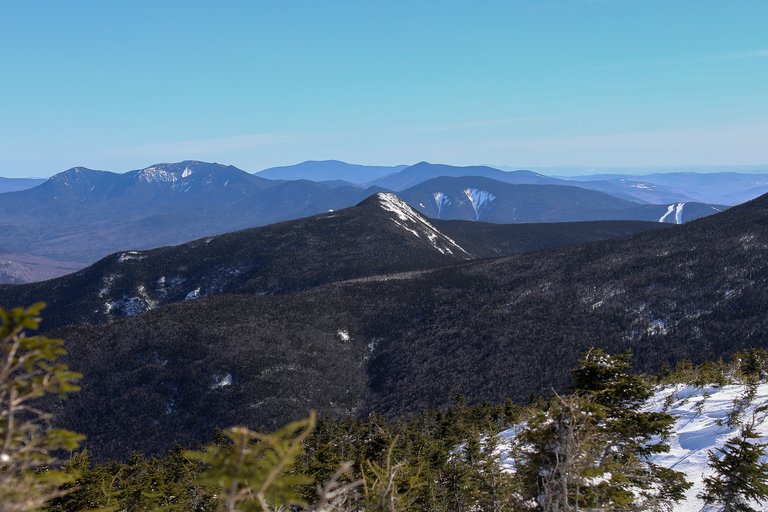 Mount Flume ridge with patches of snow under clear blue sky in White Mountains