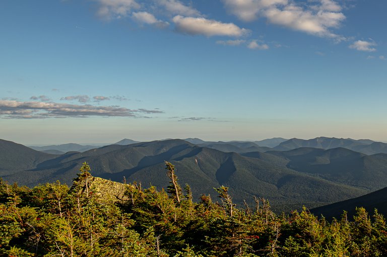 Mount Hancock ridge bathed in warm sunset light with clear blue sky and scattered clouds over White Mountains