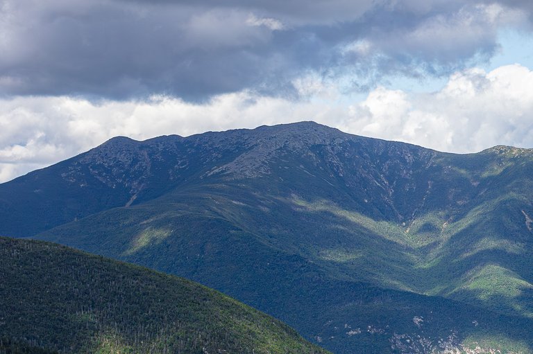 Mount Lafayette peak with forested slopes and clouds casting shadows in White Mountains