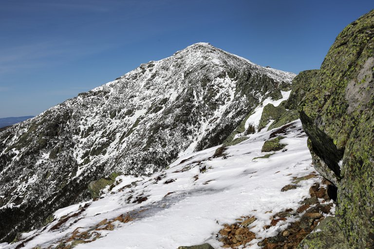 Mount Lincoln peak with snow patches and granite rocks under blue sky