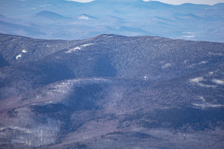 Snow-covered Mount Waumbek ridge in winter afternoon light with forested slopes