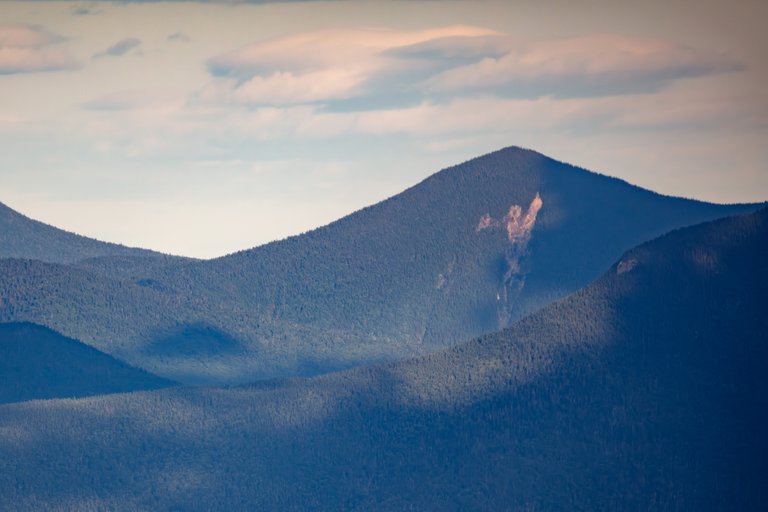 North Tripyramid mountain bathed in soft sunset light with forested ridges and shadows