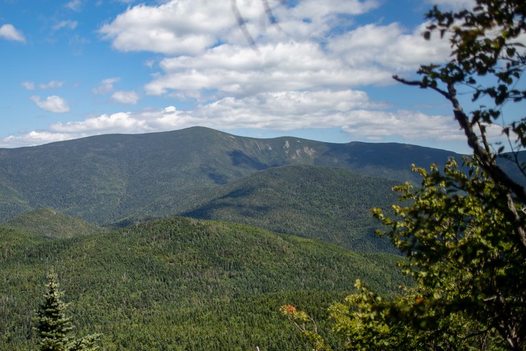 South Twin Mountain with forested ridges and blue sky with clouds in White Mountains