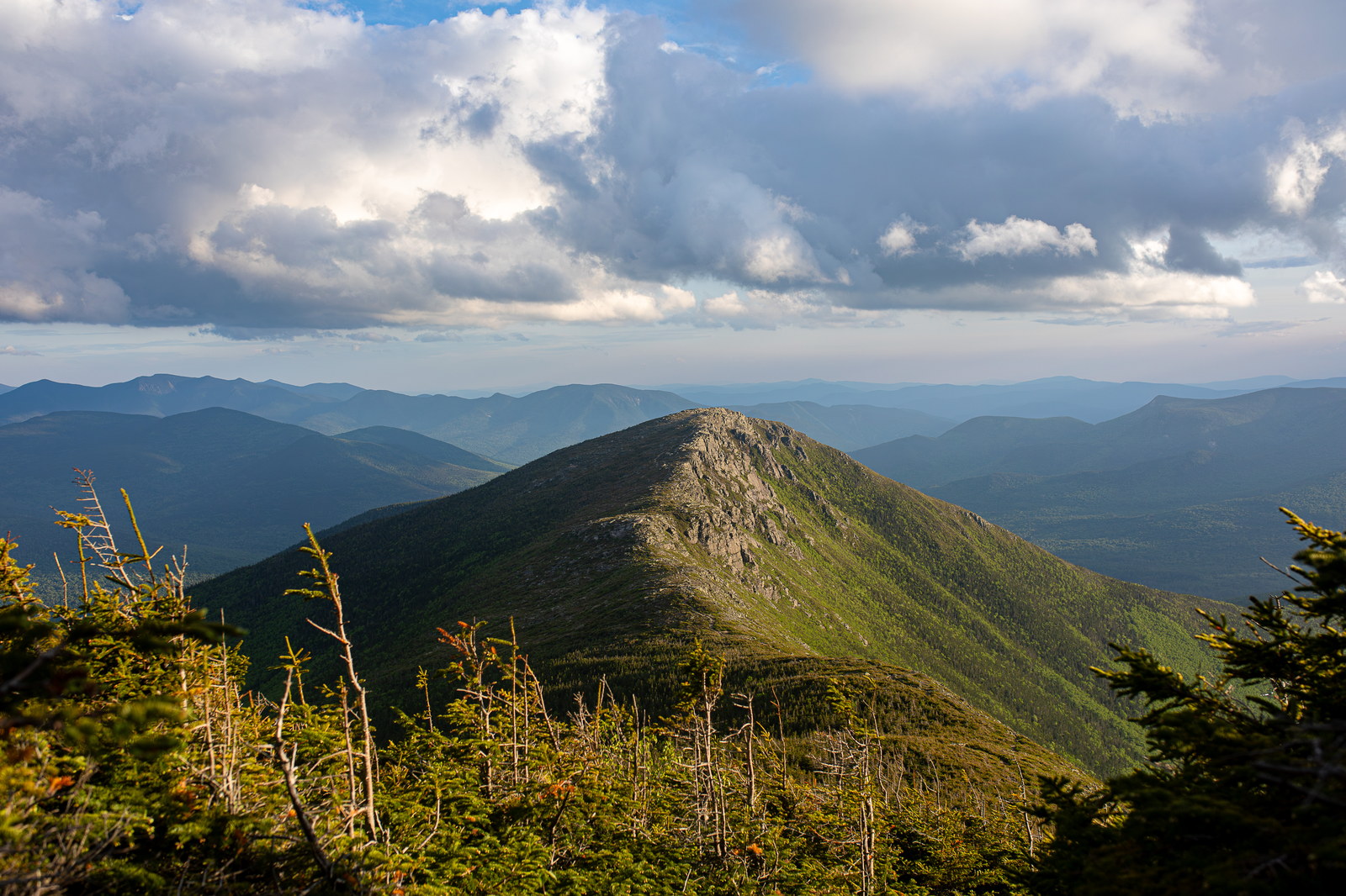 Bondcliff summit with rocky ridge and green forest under a cloudy summer sky
