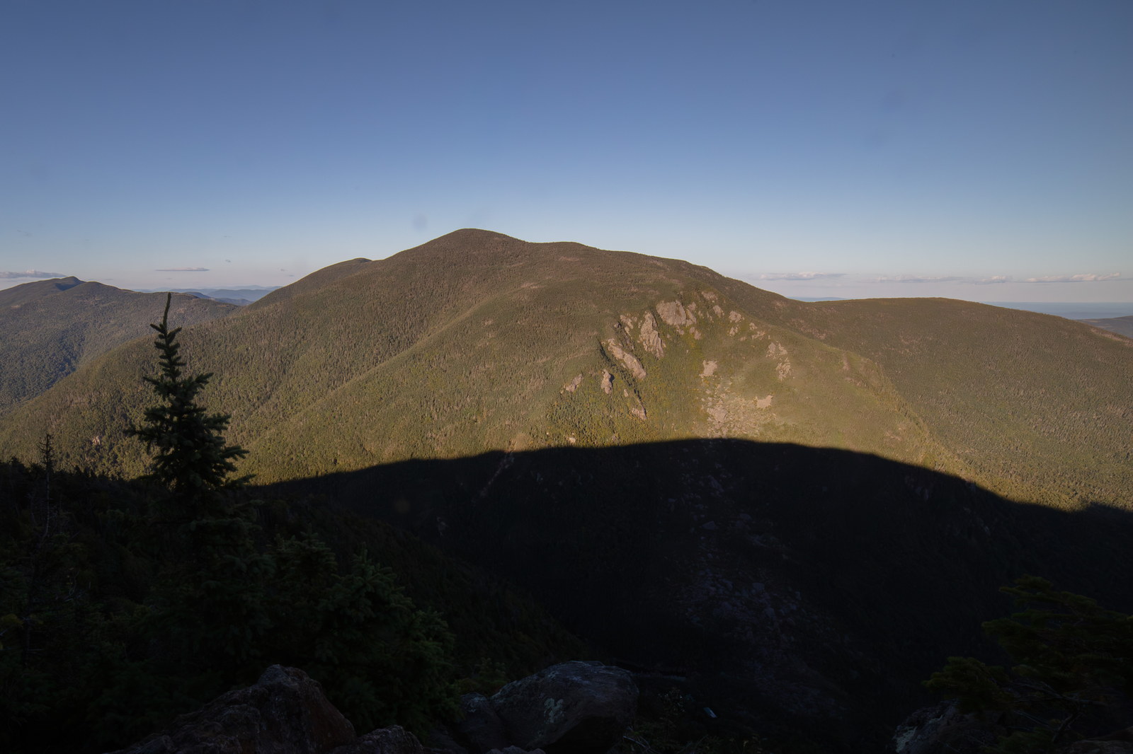 Carter Dome mountain with forested slopes and granite ledges under clear sky at sunset