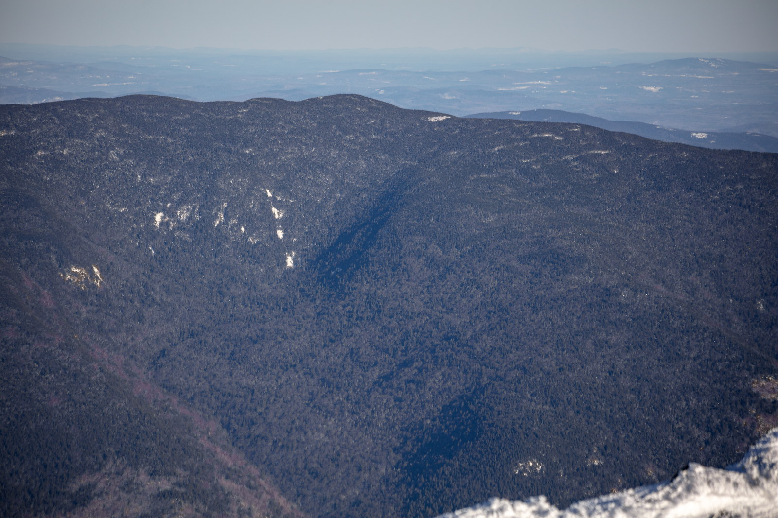 Middle Carter Mountain covered in winter forest with soft shadows and distant ridges