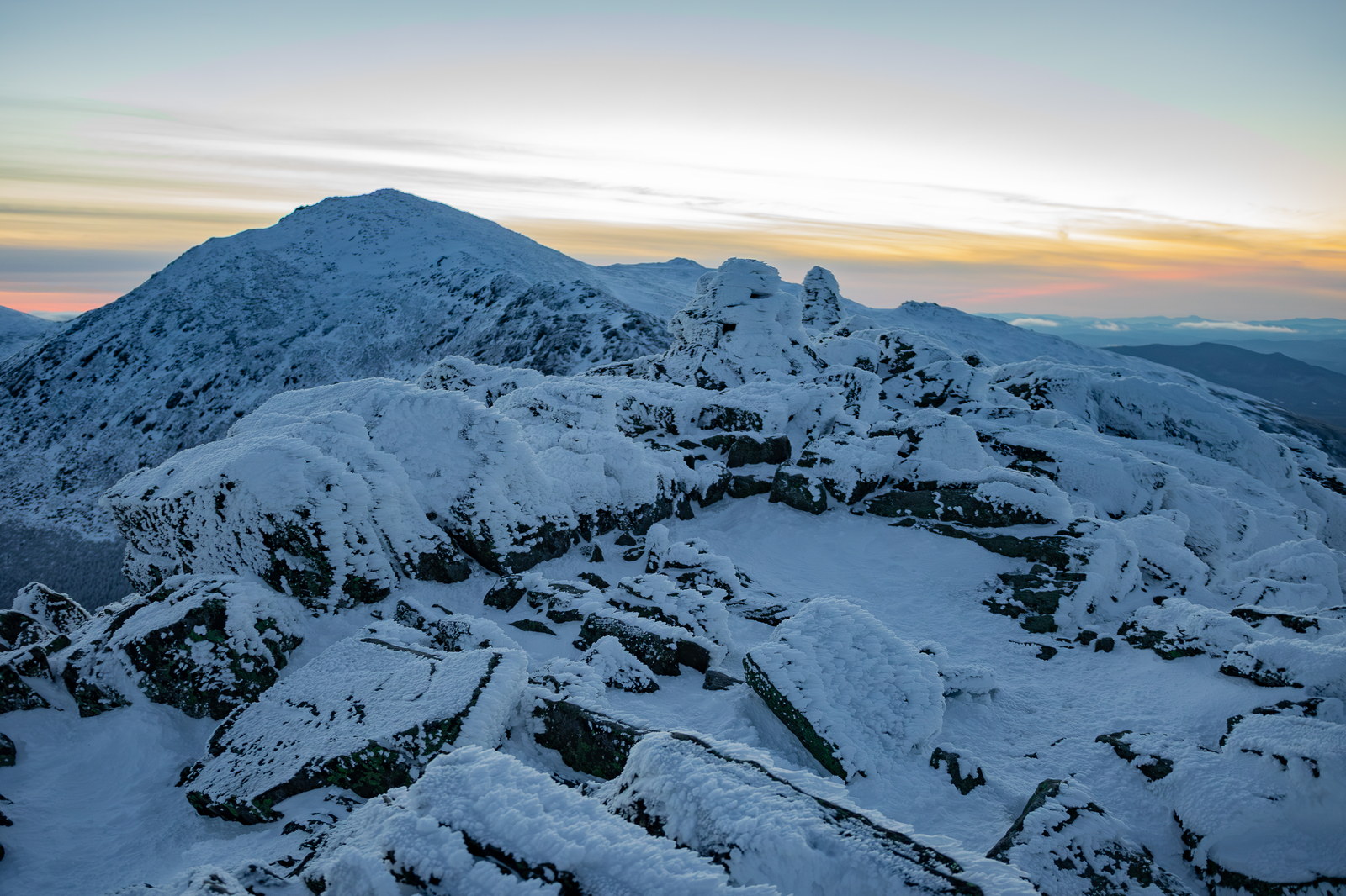 Snowy granite cairns on Mount Adams ridge at winter sunset in White Mountain National Forest