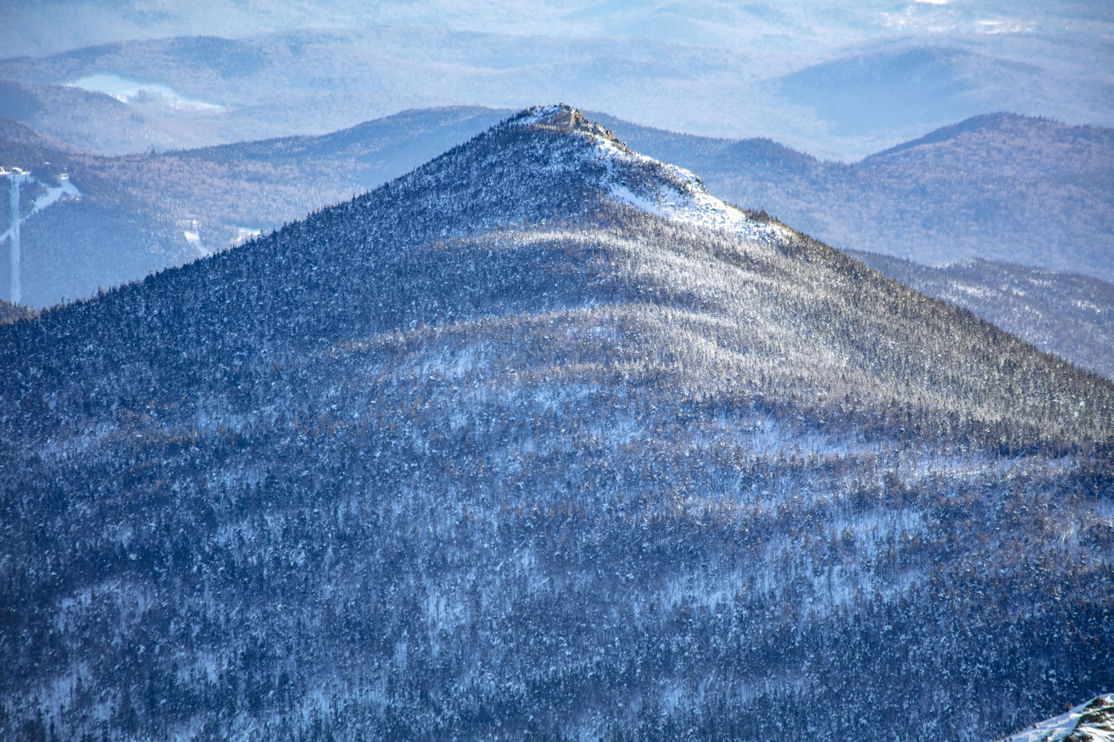 Snow-covered Mount Liberty peak with forest and granite ledges in afternoon light