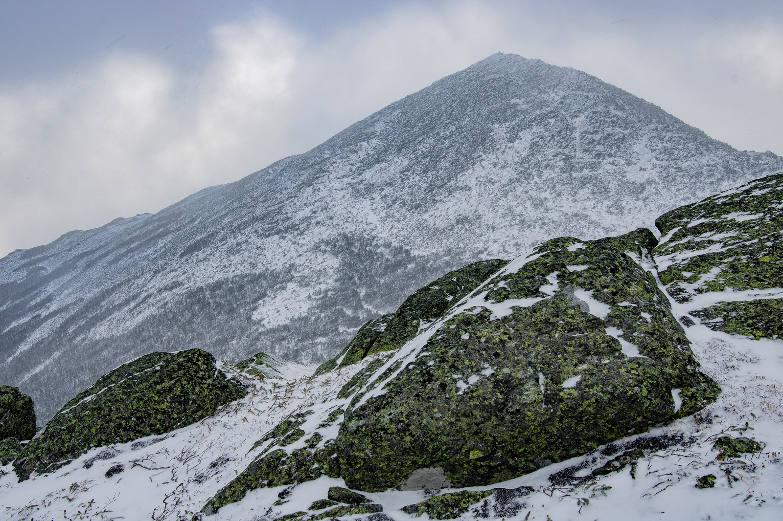 Snow-dusted rocky slopes of Mount Madison under cloudy winter sky