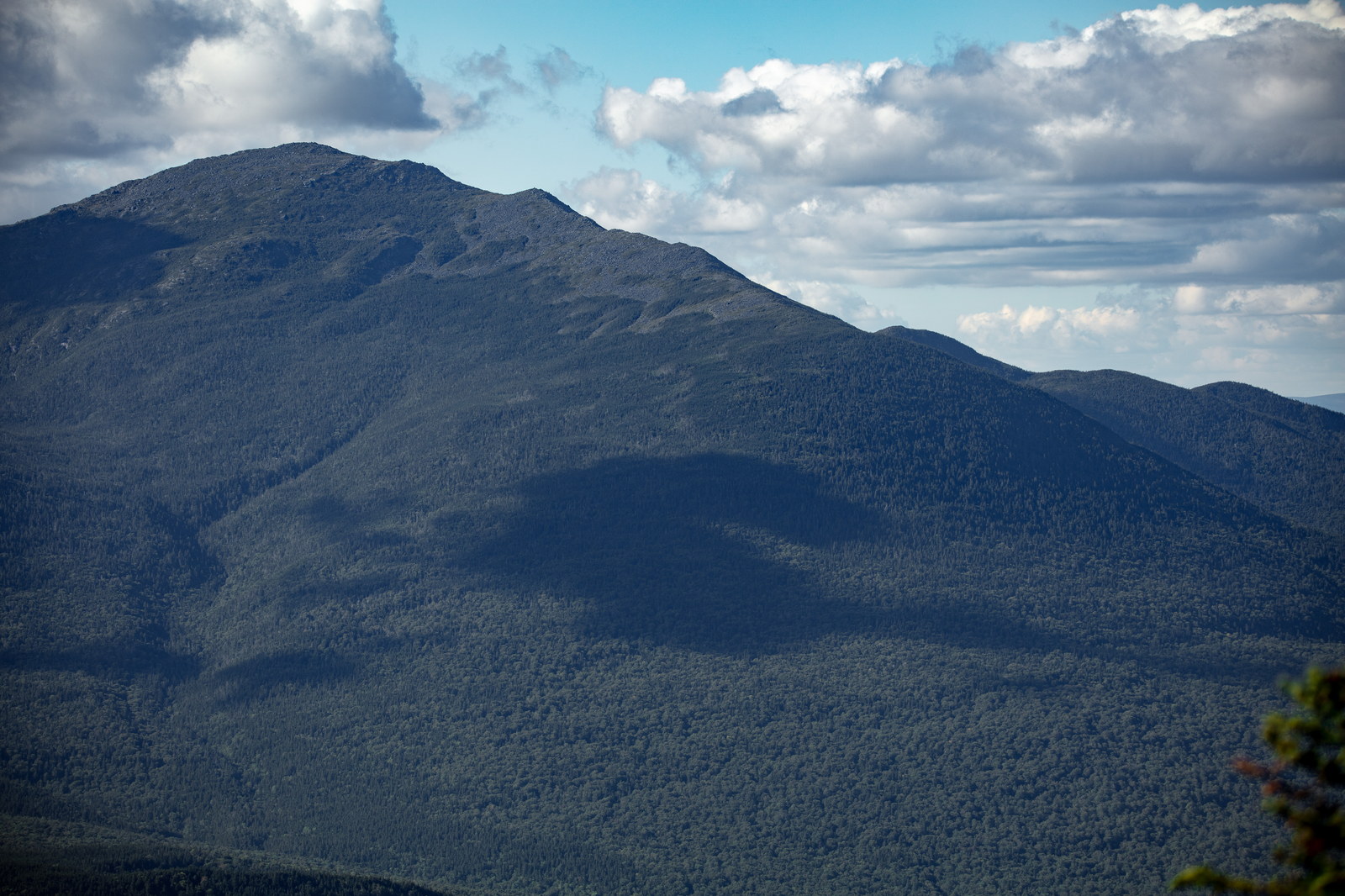 Mount Madison peak with forested slopes and cloud shadows in summer afternoon light