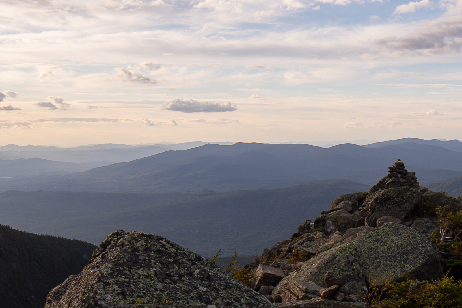 Mount Waumbek summit rocks with distant mountain ridges under soft sunset sky