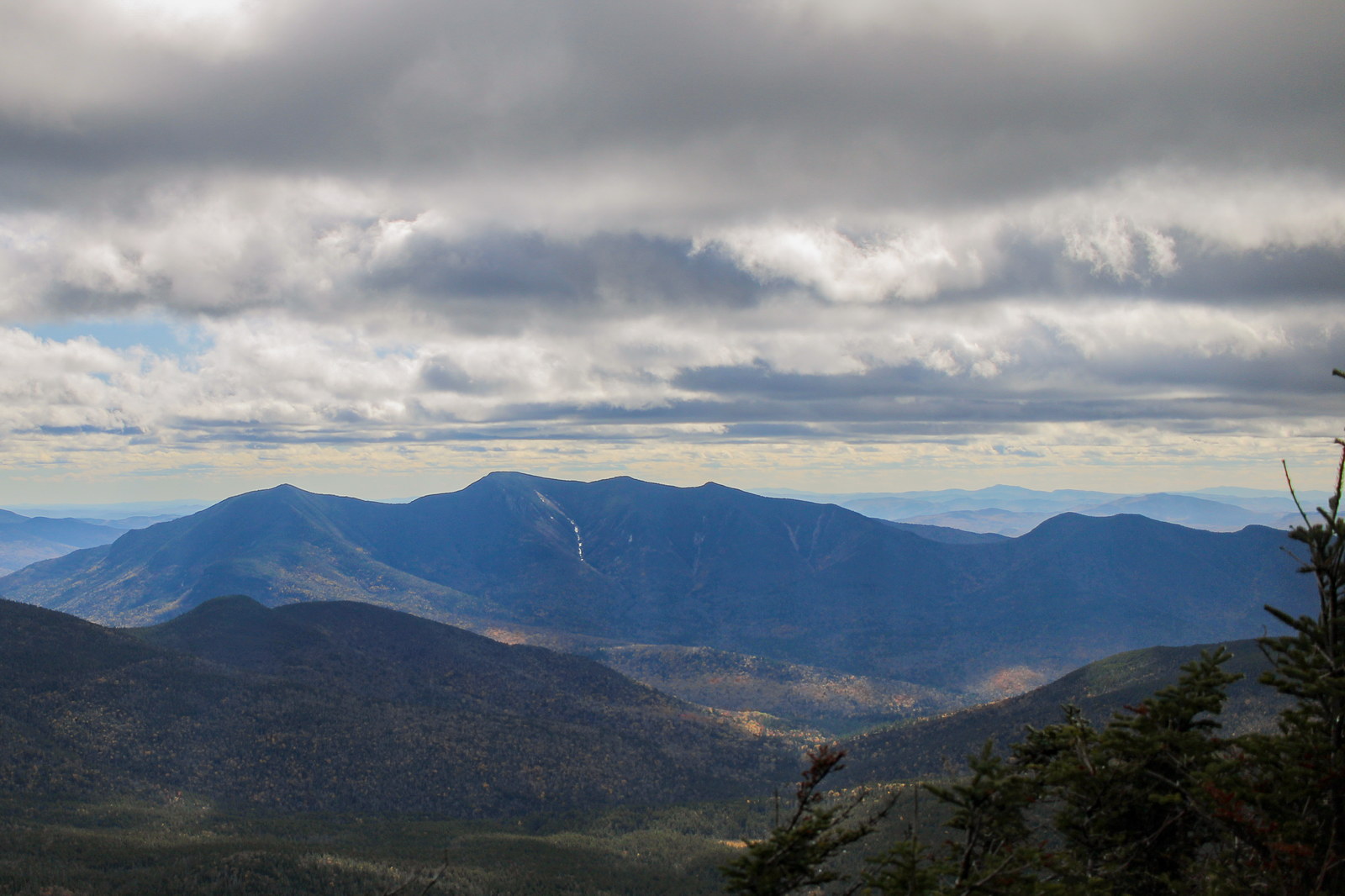 North Tripyramid mountain ridge in White Mountains with cloudy sky and fall forest