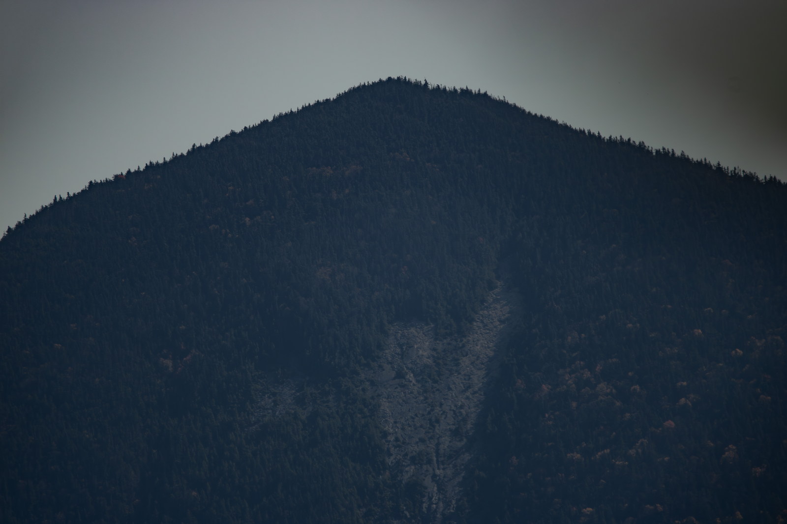North Tripyramid summit with granite scar and dense forest under clear fall sky