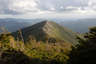 Forested mountain ridge and summit of Bondcliff in the White Mountain National Forest under a partly cloudy sky.
