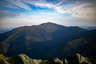 Forested mountain ridge and summit of Mount Washington in the White Mountain National Forest under a partly cloudy sky.