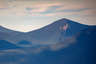 Forested mountain ridge and summit of North Tripyramid in the White Mountain National Forest under a partly cloudy sky.