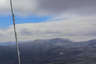 Forested mountain ridge and summit of South Kinsman Mountain in the White Mountain National Forest under a partly cloudy sky.