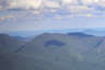 Forested mountain ridge and summit of Wildcat Mountain - A Peak. in the White Mountain National Forest under a partly cloudy sky.