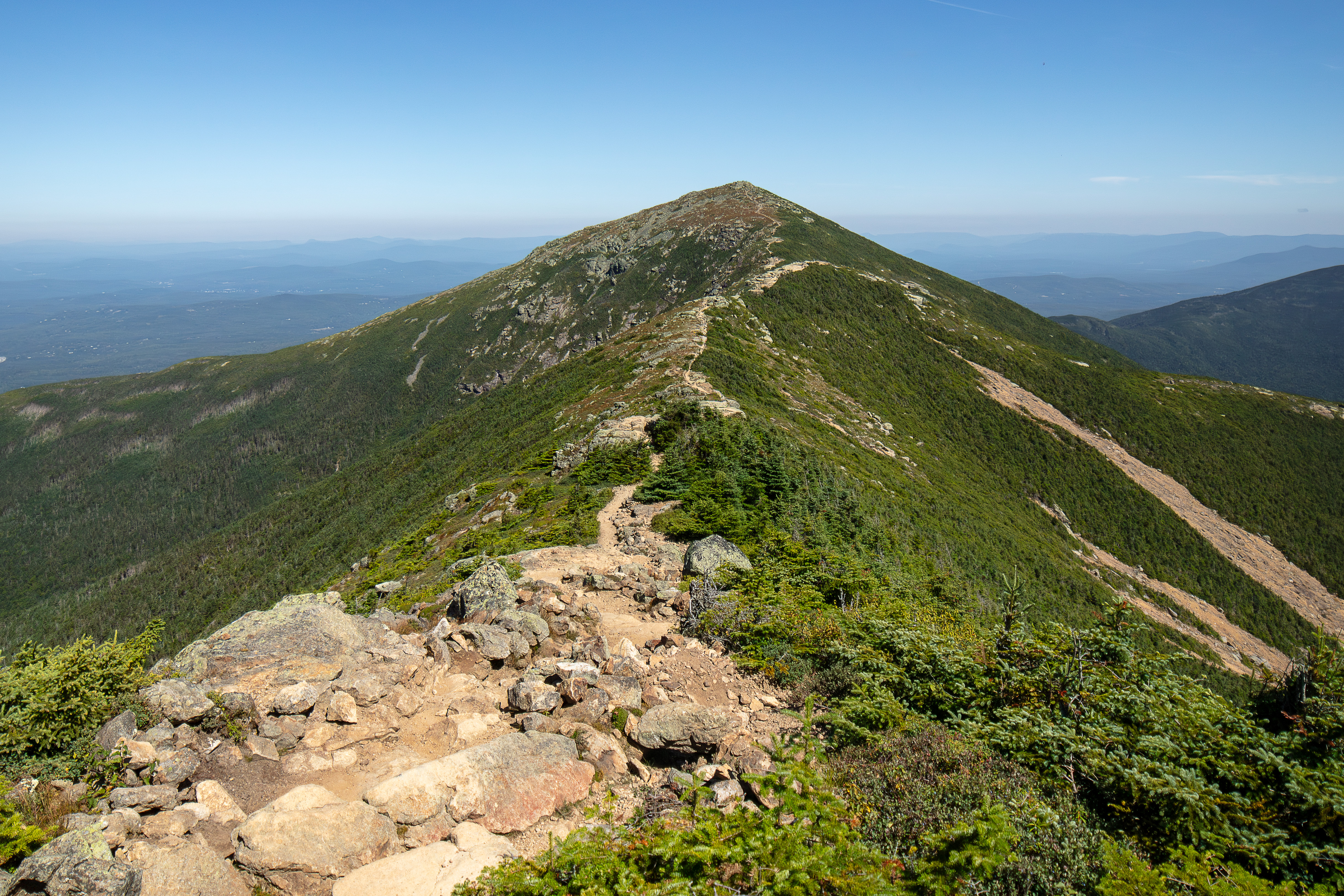 Forested mountain ridge and summit of Mount Lafayette in the White Mountain National Forest under a partly cloudy sky.
