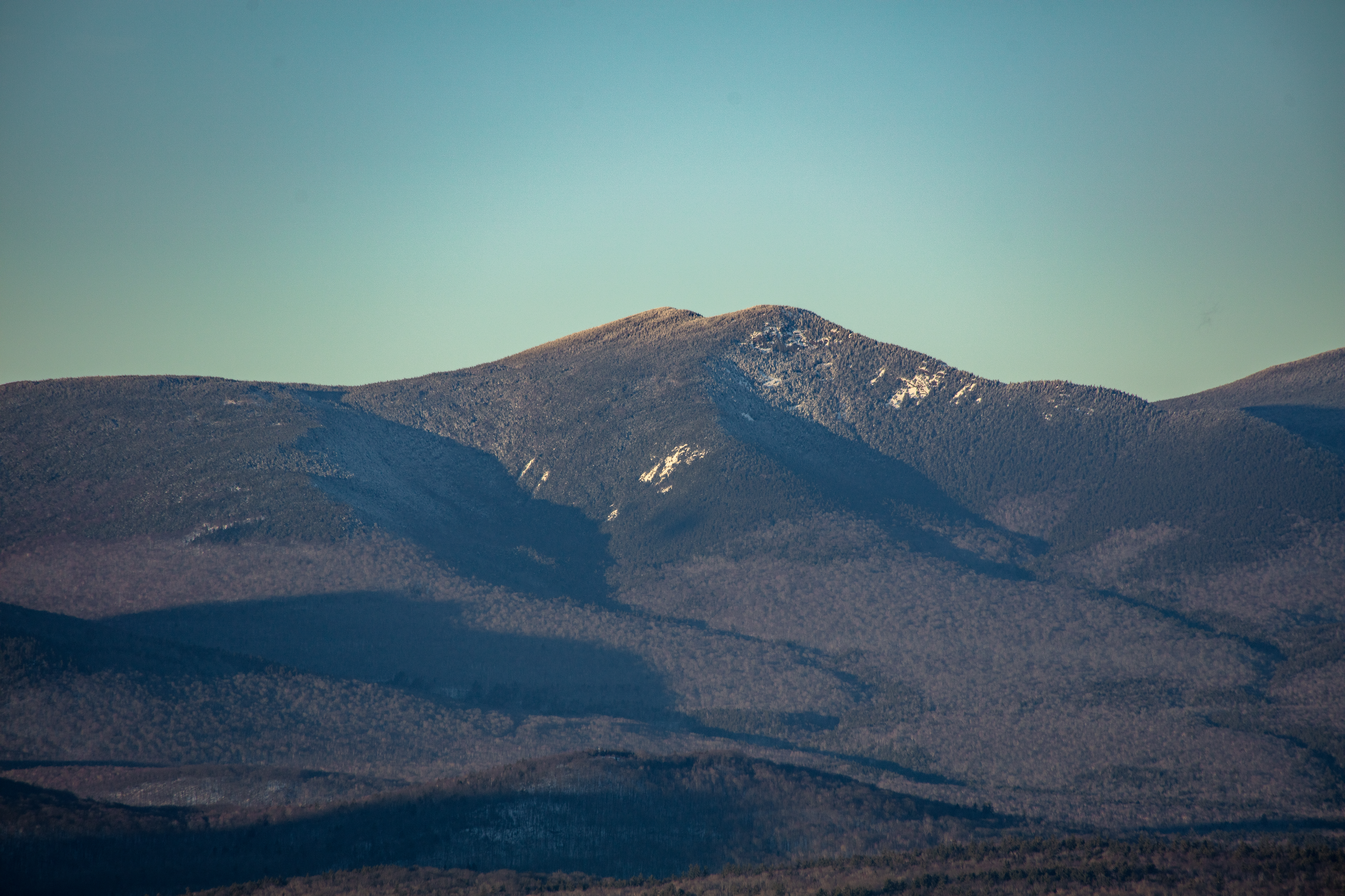 Mount Whiteface in winter afternoon light with snow patches and clear blue sky