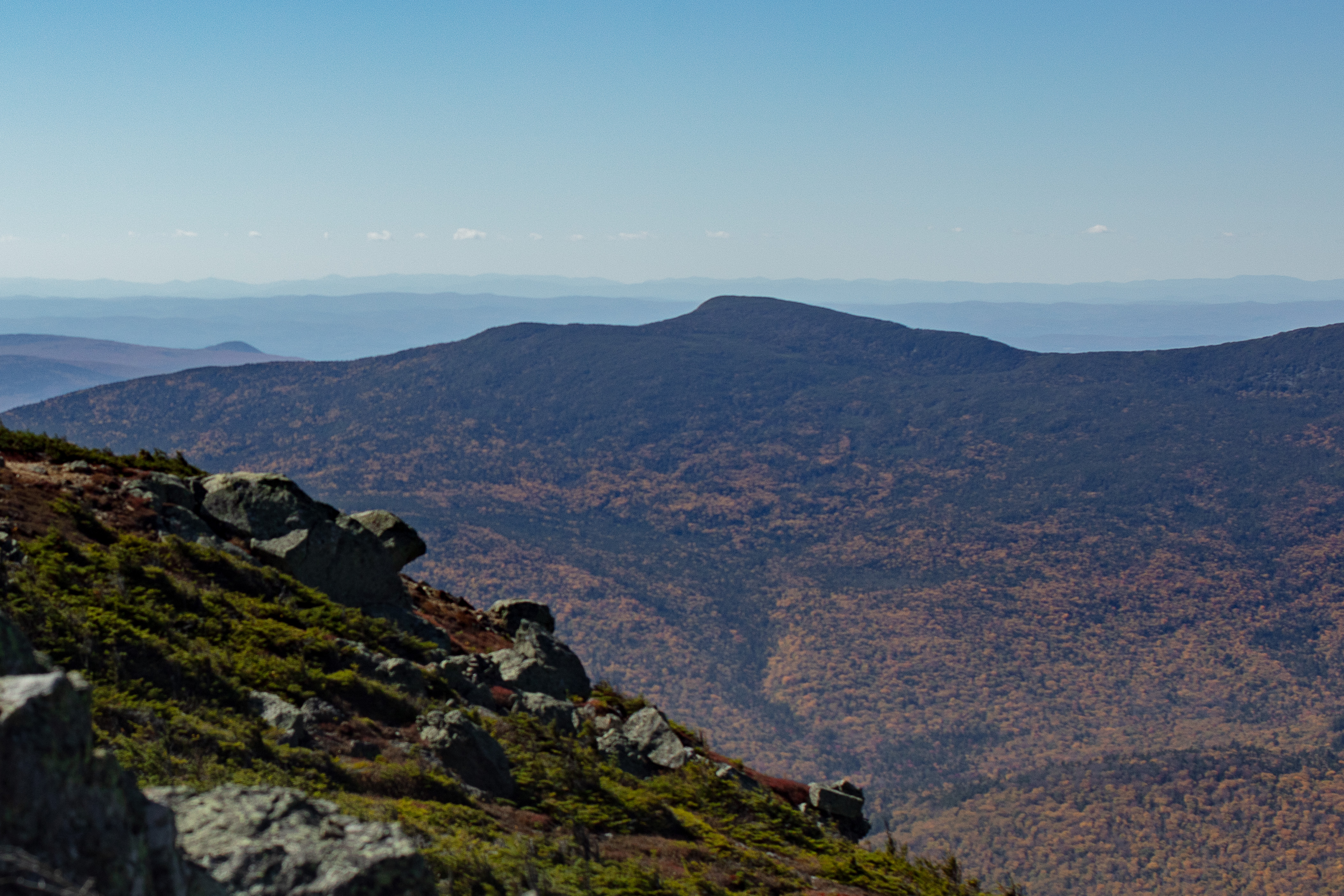 South Kinsman peak with fall foliage and rocky ridge under clear blue sky
