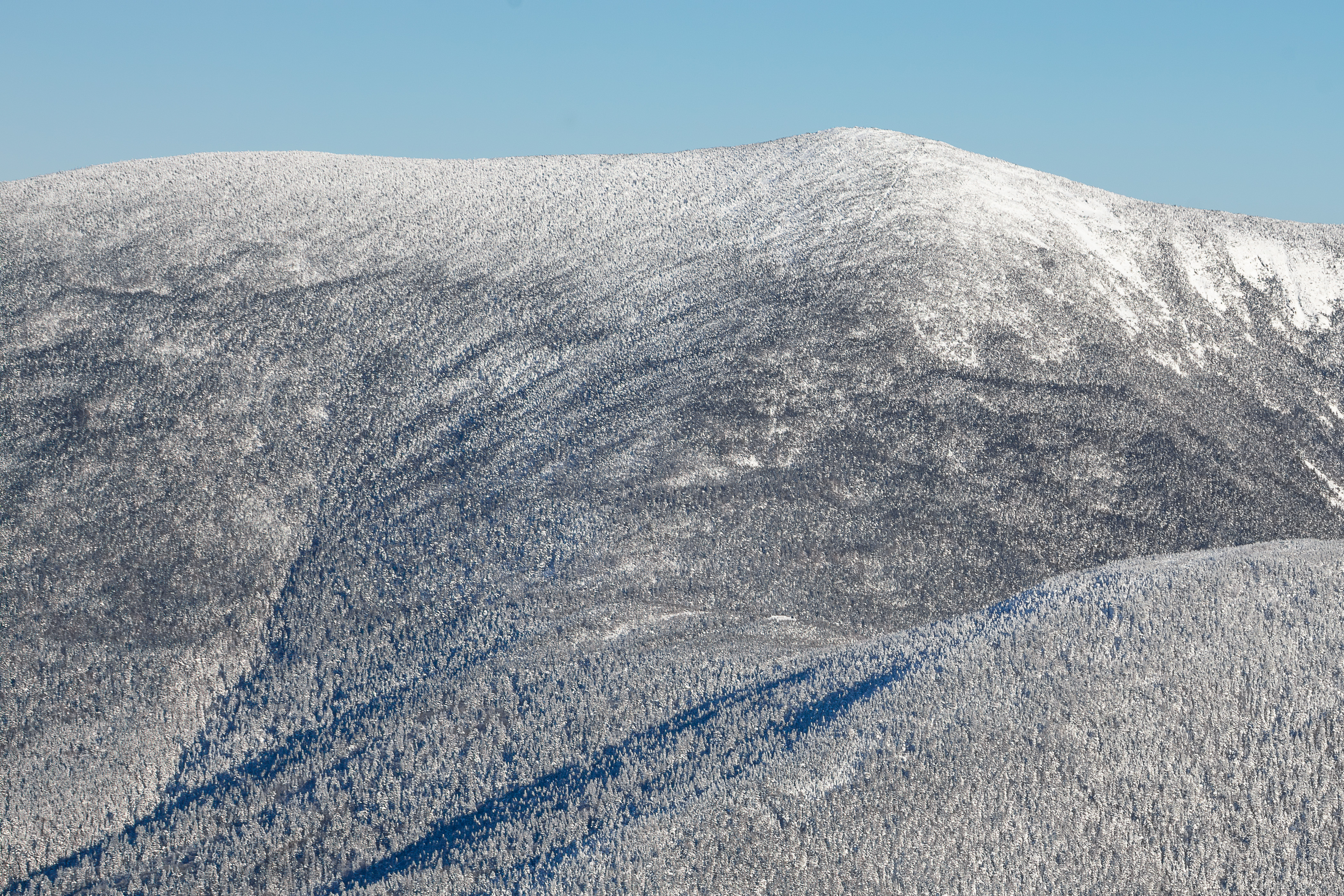 Snow-covered South Twin Mountain ridge under clear blue sky in winter